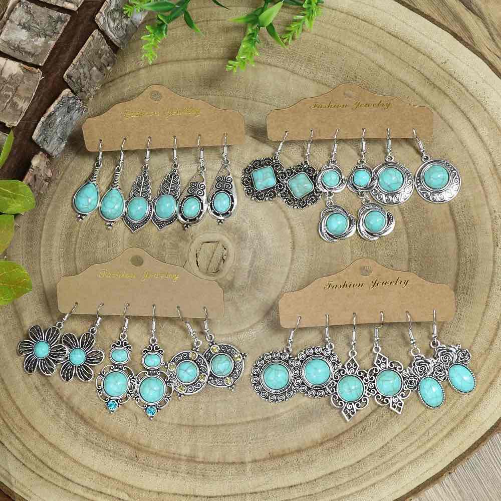 Close-up partial view showing the double-drop and large round oxidised silver turquoise earrings on a brown display card.