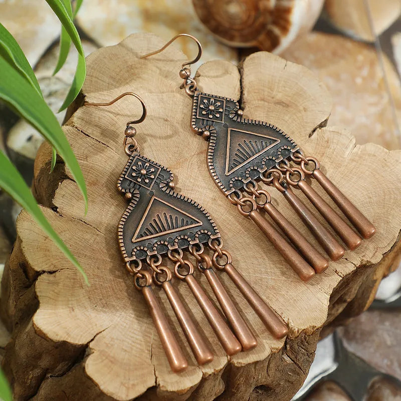 Long oxidised tribal dangle earrings with geometric patterns and tassel drops on wooden backdrop - front view | Zuzu's Trove