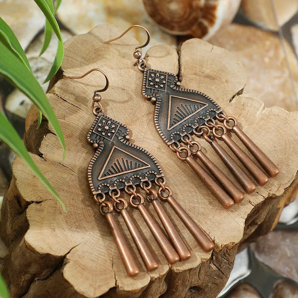 Long oxidised tribal dangle earrings with geometric patterns and tassel drops on wooden backdrop - front view | Zuzu's Trove
