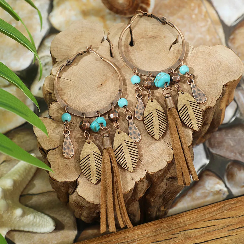 Pair of hoop earrings with tassels and turquoise beads on a natural wood background