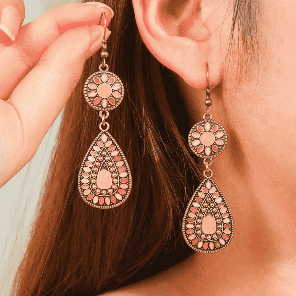 Close-up of a person wearing ornate earrings with a blurred background