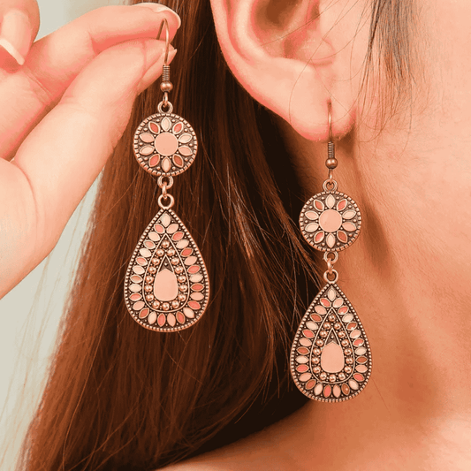 Close-up of a person wearing ornate earrings with a blurred background