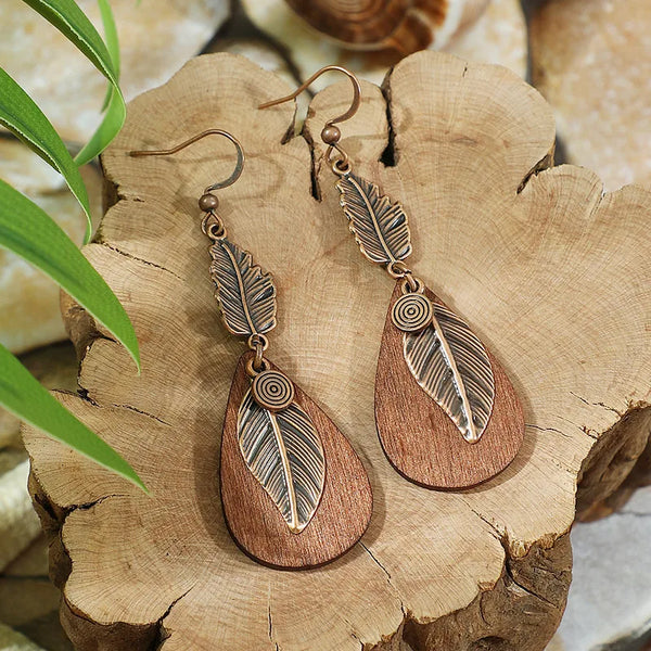 Oxidised feather and wood drop earrings on wooden surface - front view | Zuzu's Trove