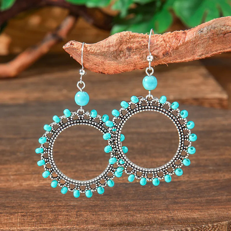 Close-up of the left oxidised silver drop earring, showing the intricate beaded rim, the single turquoise top bead, and the f