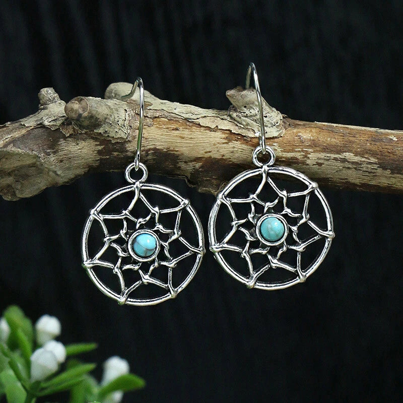 Close-up of the left oxidised silver drop earring, showing the intricate web pattern around the round turquoise stone and the