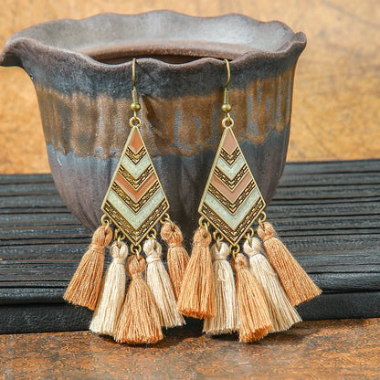 Geometric earrings with tassels on a rustic background