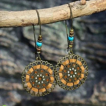Ornate earrings with turquoise beads hanging on a branch