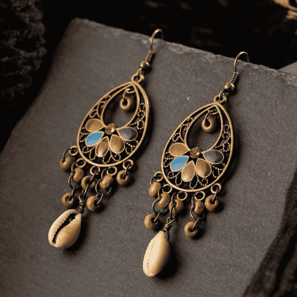 Ornate earrings with intricate designs and shell-like elements on a dark surface