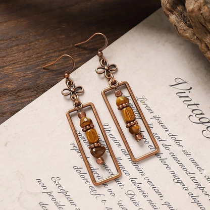 Oxidised antique boho rectangle dangle earrings with earthy beads, laid on vintage paper - Front view | Zuzu's Trove