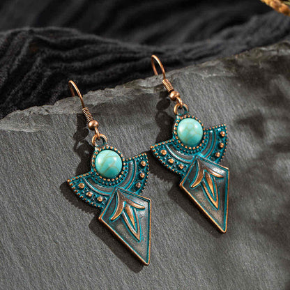 Pair of antique turquoise drop earrings with oxidised metal and tribal patterns, displayed on a dark grey surface with black 