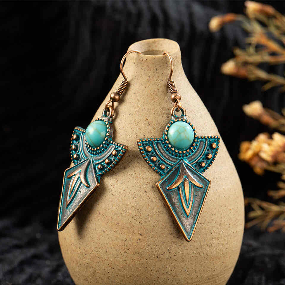 Close-up of the left antique turquoise earring's hook and upper section, showing metal texture and round turquoise stone.