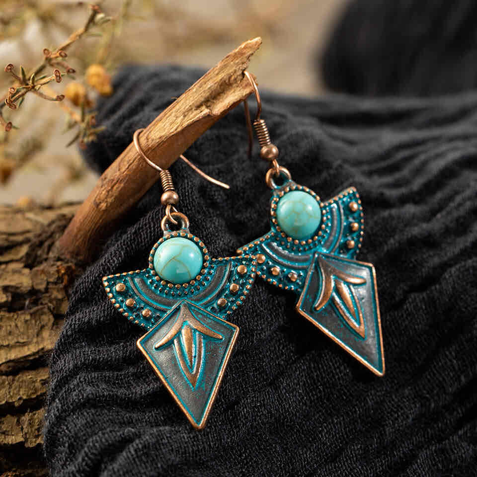 Detail view of the right antique turquoise earring, highlighting the round stone and intricate dot work on the fanned metal.